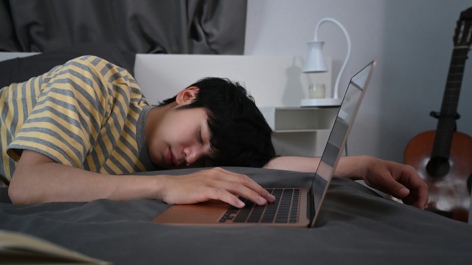 boy sleeping with laptop on the bed