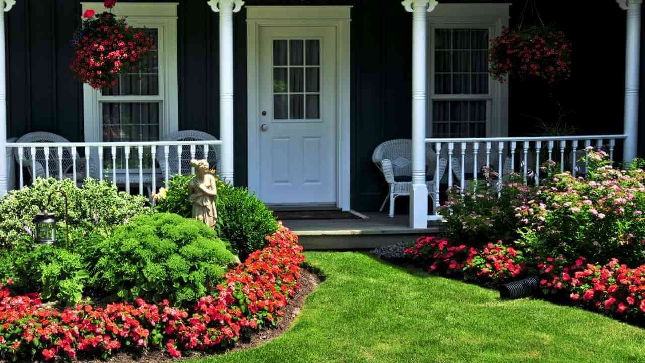 A white front porch with colorful flowers in bloom.