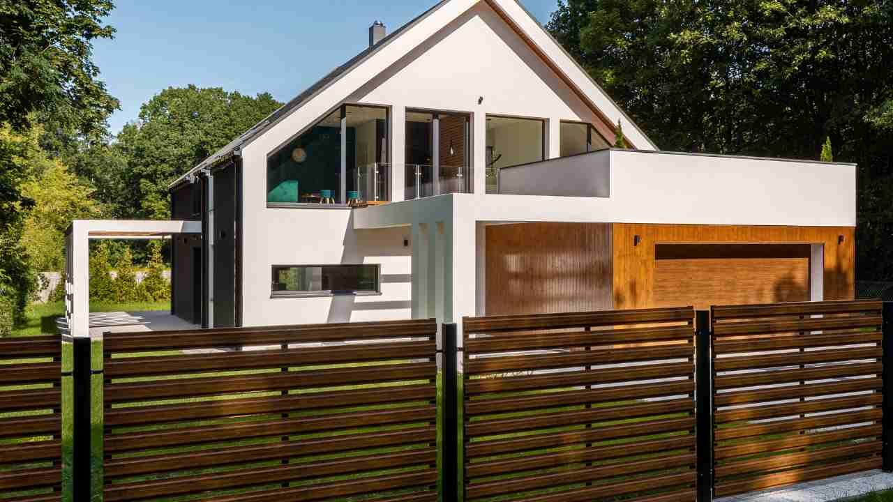 A sleek modern home enclosed by a wooden fence.