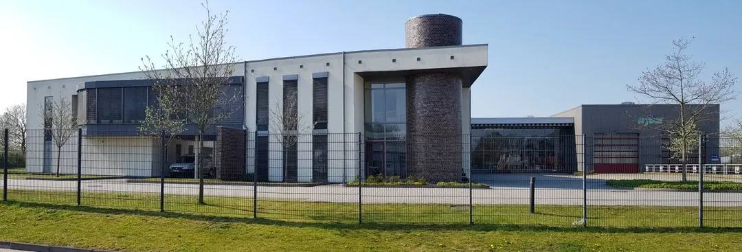 Ein großes Gebäude mit vielen Fenstern ist von einem Zaun umgeben.