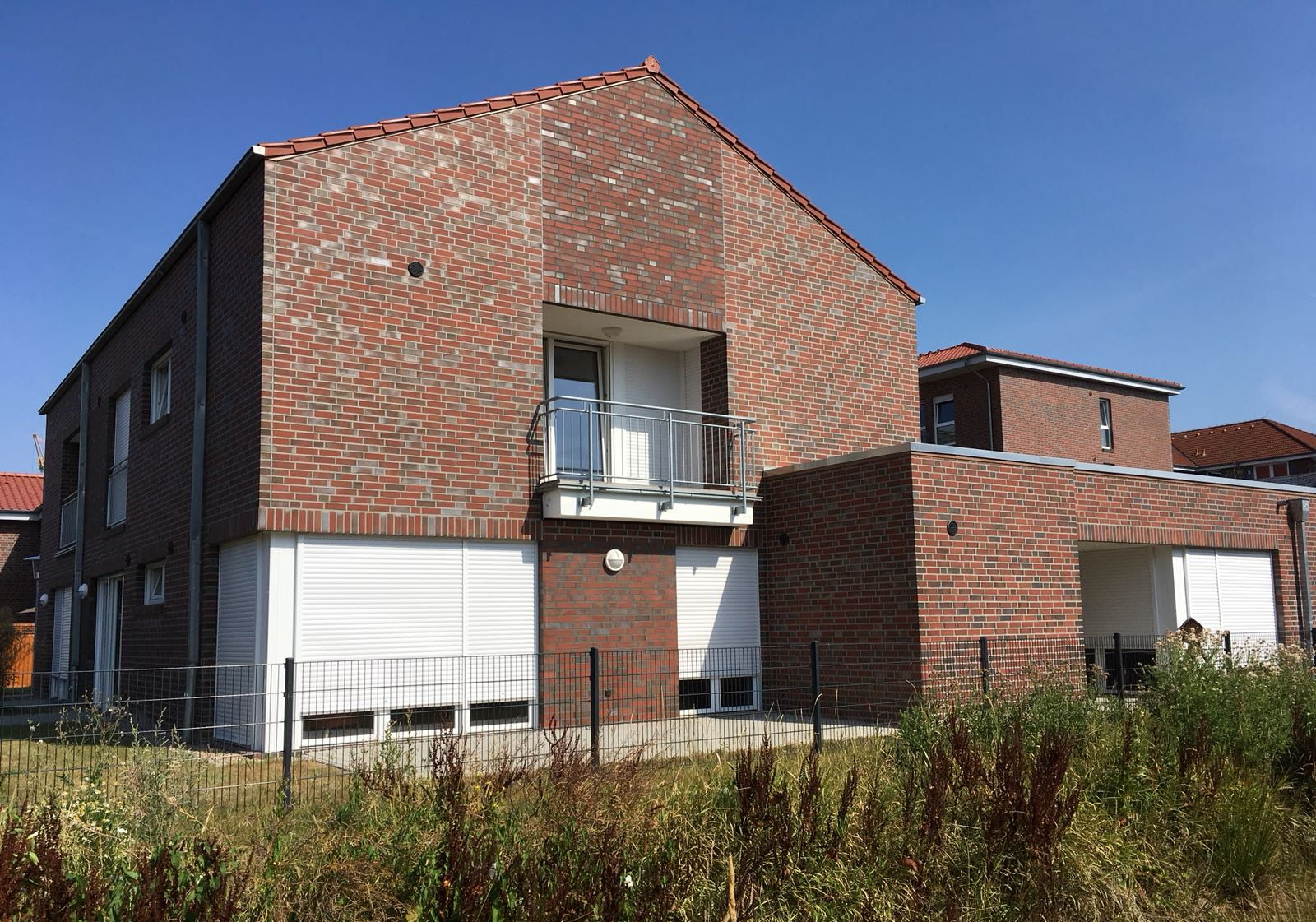 Ein großes Backsteingebäude mit Balkon und Fensterläden