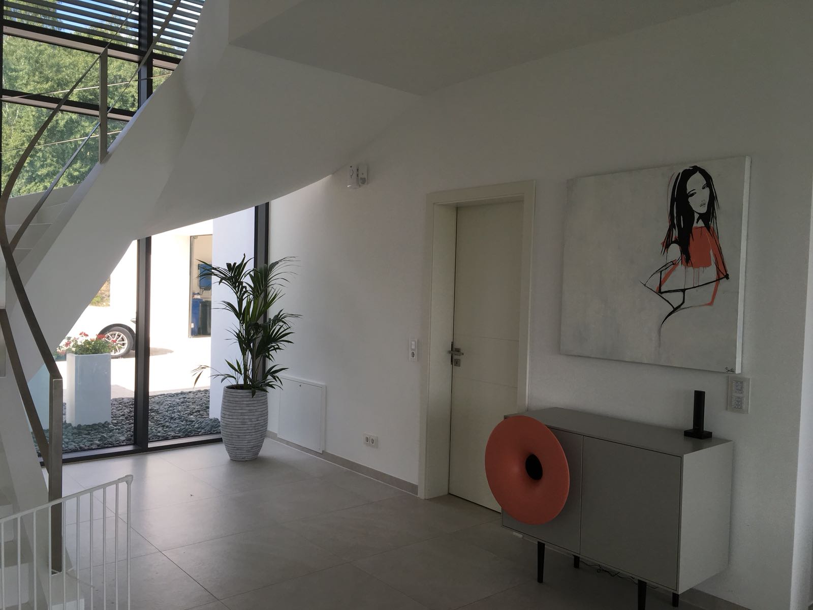 Ein Flur mit einem Gemälde an der Wand und einer Pflanze in einem Topf.