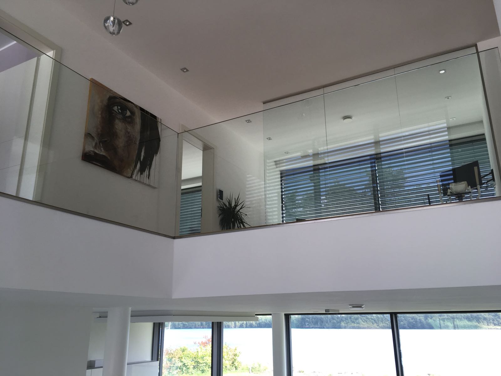 Ein Wohnzimmer mit einem Glasgeländer und einem Gemälde an der Wand.