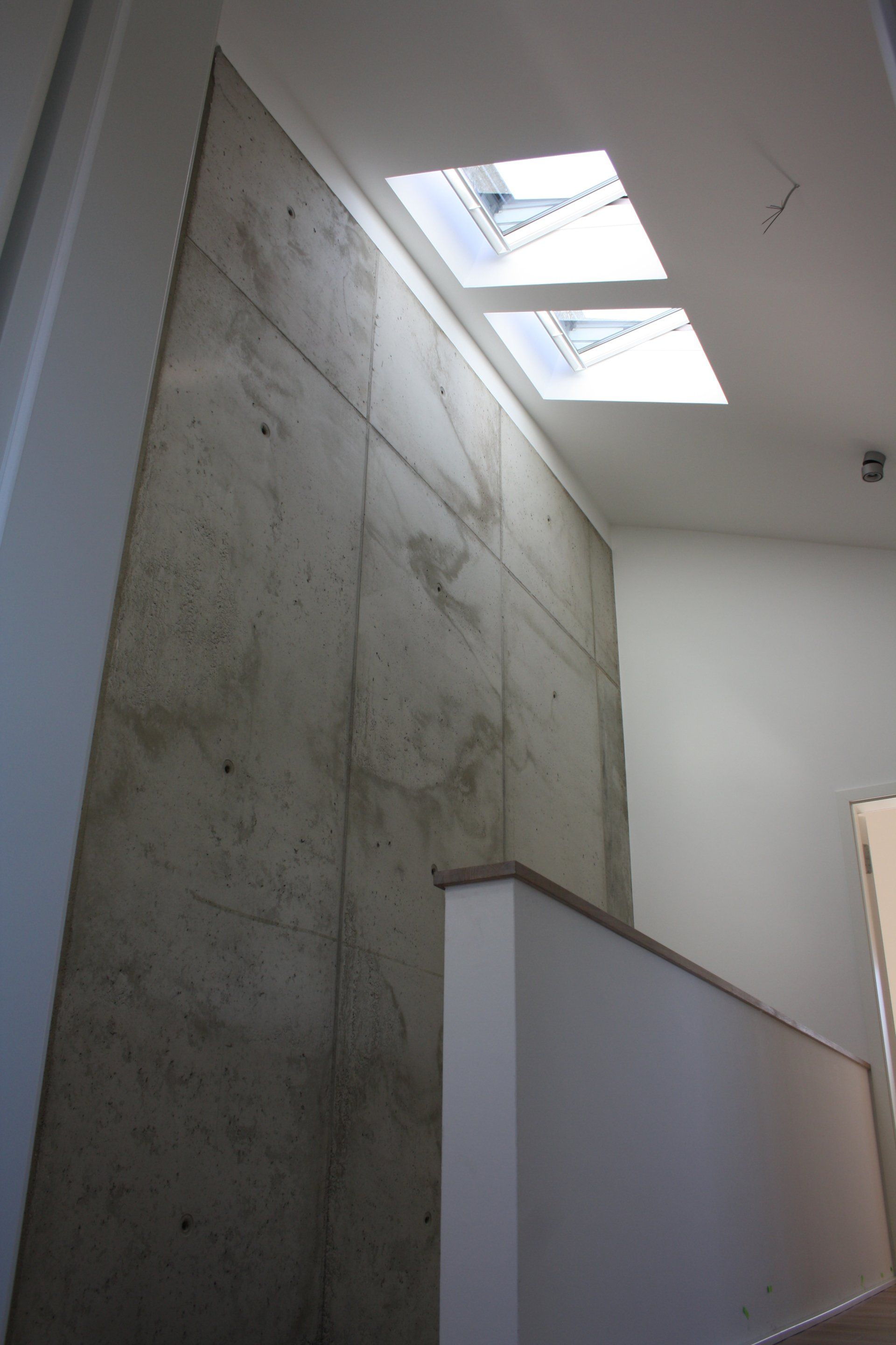 Ein Flur mit einer Betonwand und zwei Oberlichtern an der Decke.