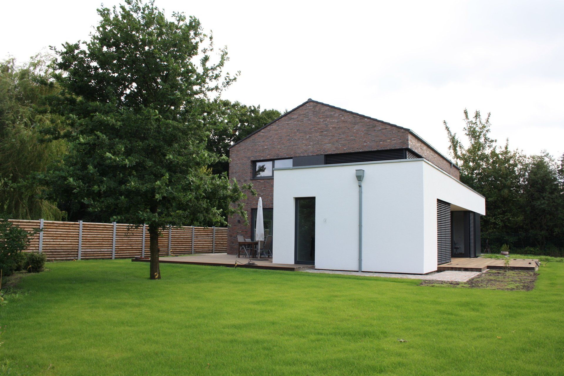 Ein weißes Haus mit einem Ziegeldach steht inmitten eines üppigen grünen Feldes