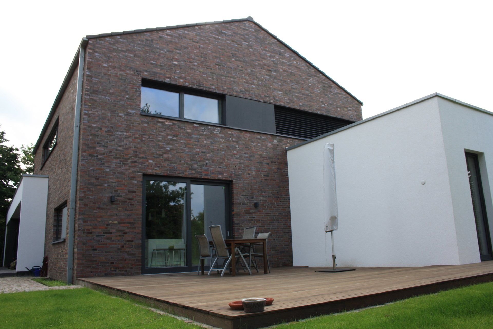 Ein großes Backsteinhaus mit einer Holzterrasse davor.