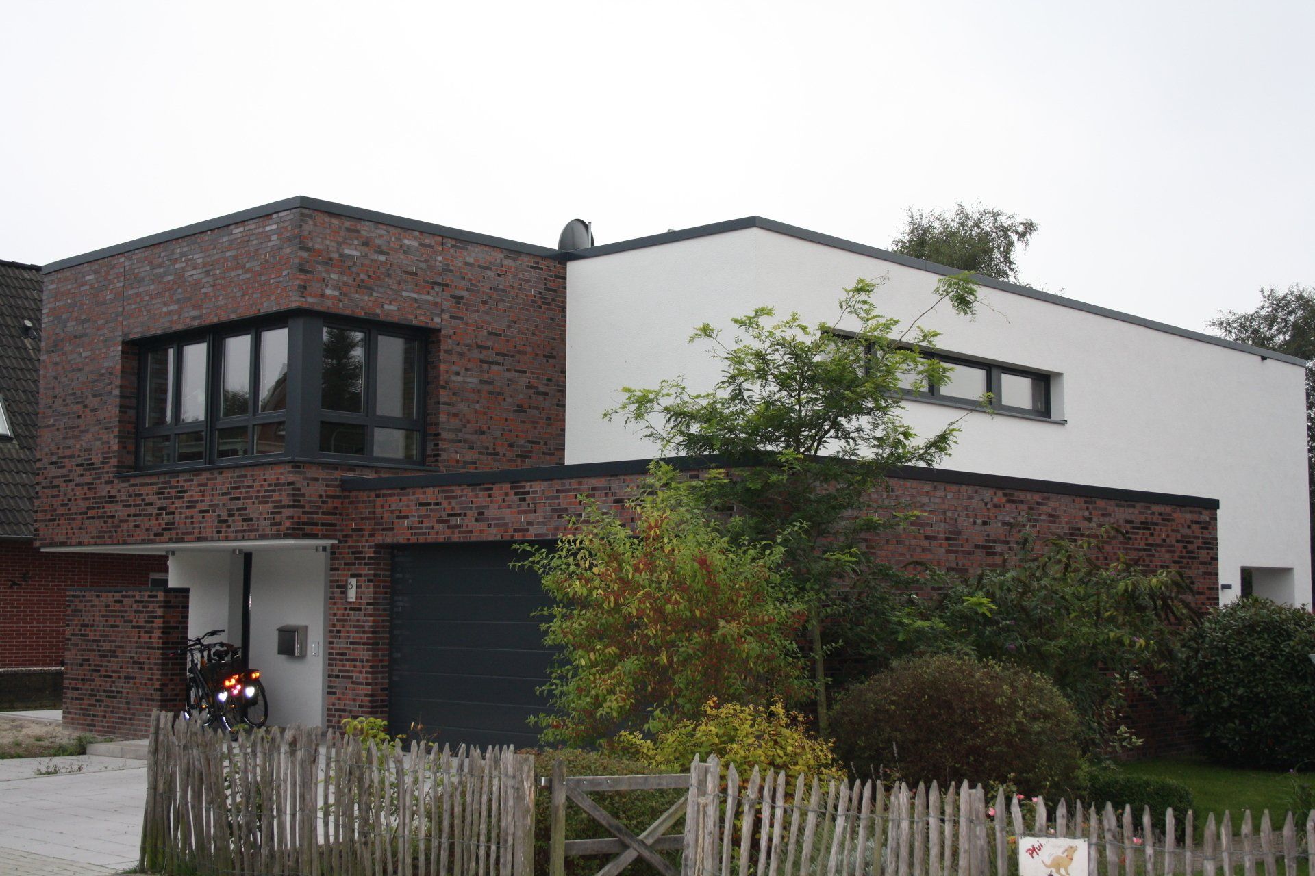 Ein großes weißes Backsteinhaus mit einem Holzzaun davor.