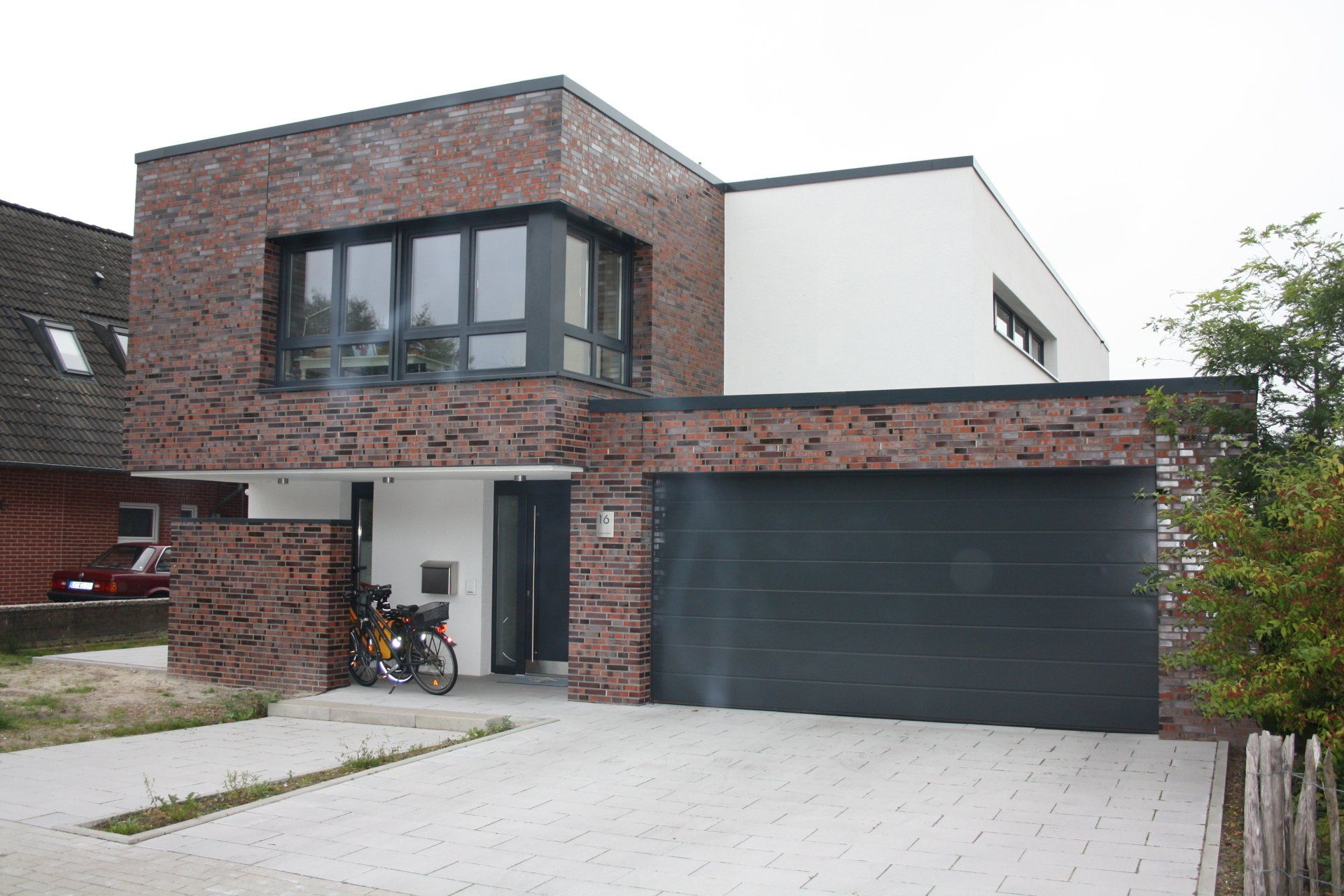 Ein Backstein- und Weißhaus mit einem schwarzen Garagentor