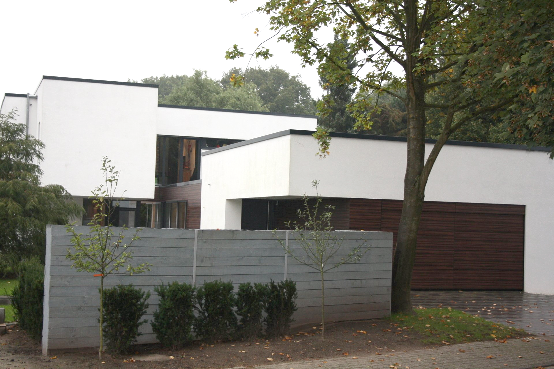 Ein modernes weißes Haus mit einem hölzernen Garagentor