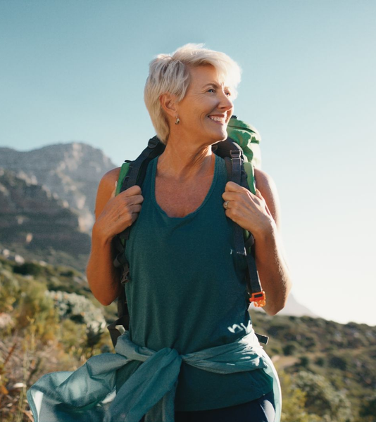 Woman with backpack smiles while hiking outdoors.