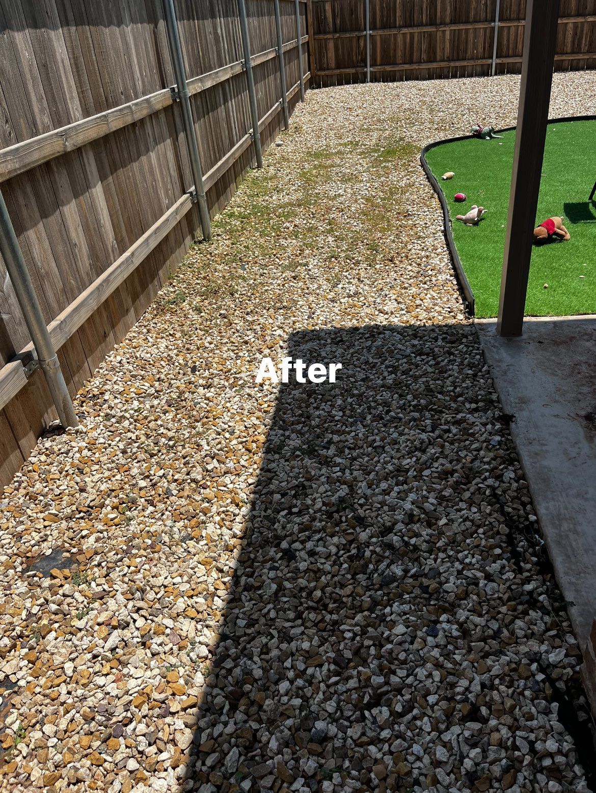 A gravel path in a backyard with a wooden fence in the background.