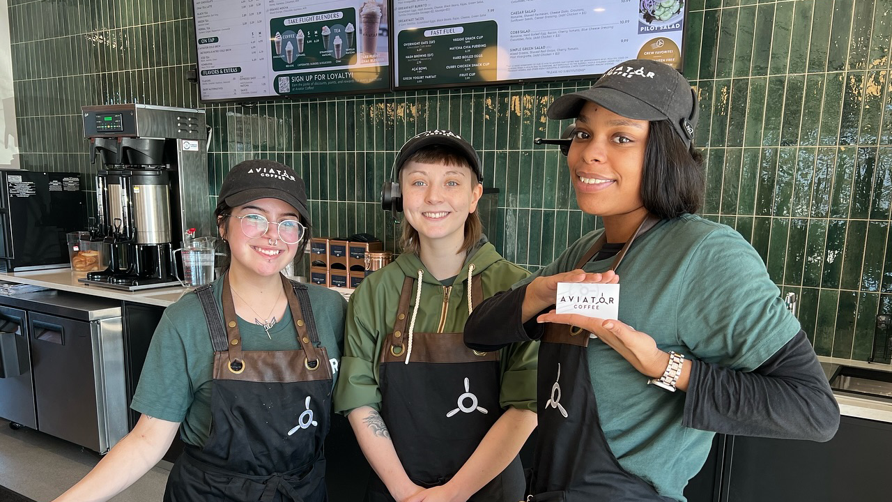 Three women are standing next to each other in a restaurant holding a card.