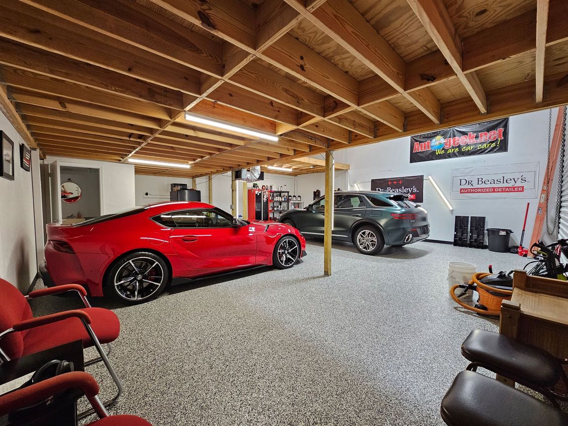 a white car is parked in a dark garage next to other cars .