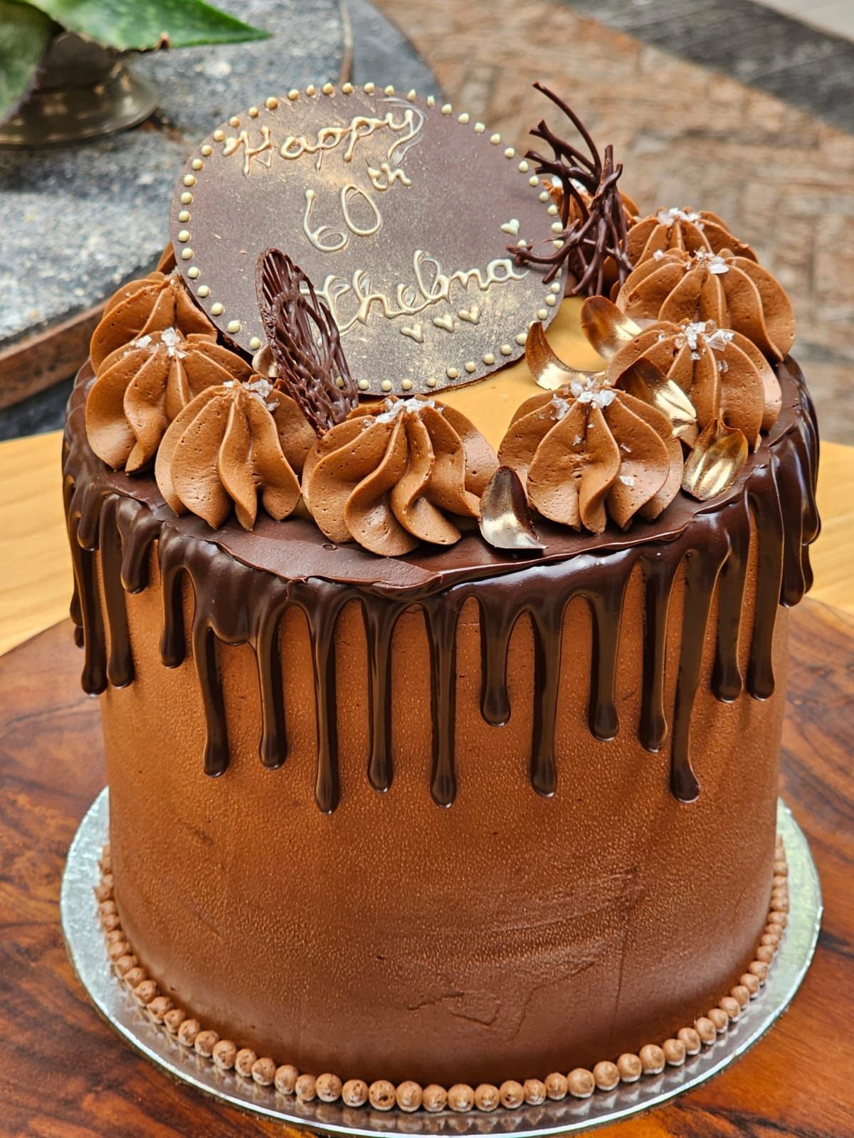 Burger with toppings, fries, beer, and a bottle on a wooden board.