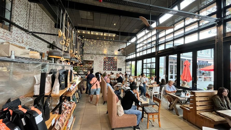 People enjoying meals at a restaurant, some people working on laptops, the other eating; people in the background.