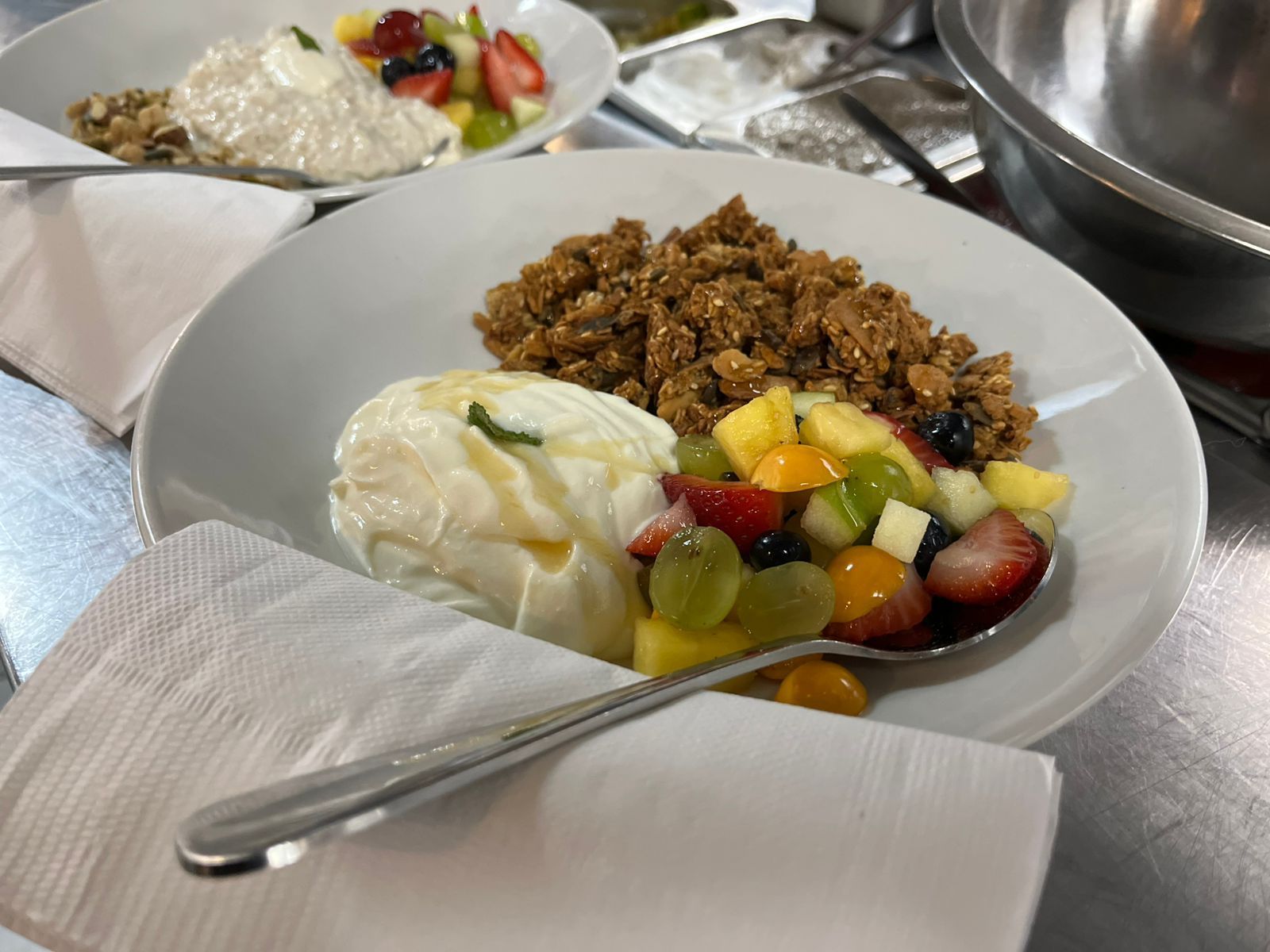 Plates of food: burger with fries, a round patty with a bun, and flatbread with arugula on a wooden table.