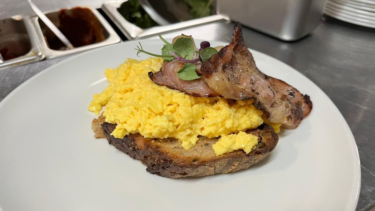 Overhead shot of a plate with tomatoes, olives, cucumber, cheese, and flatbread, next to a spilled sauce and tomatoes.