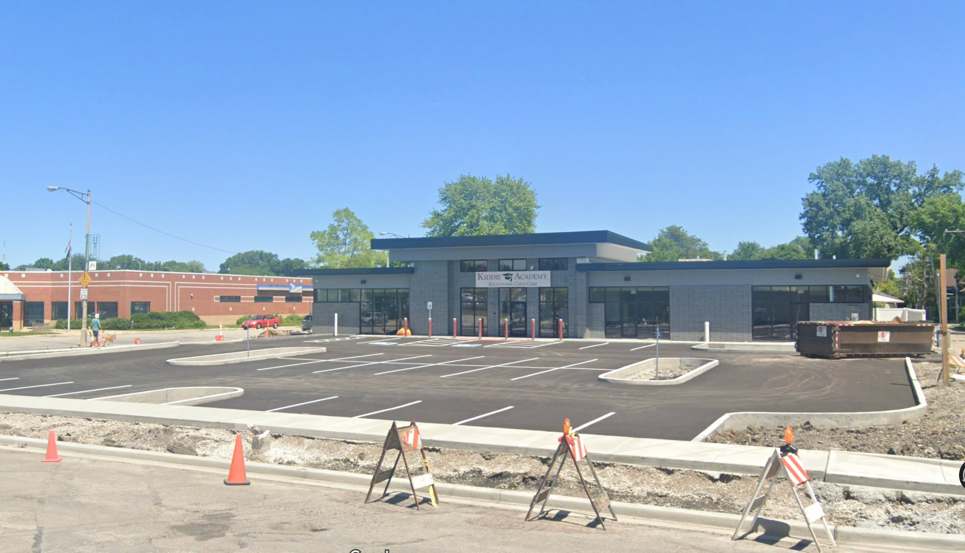 New gas station under construction with parking lot, orange cones, and blue sky.