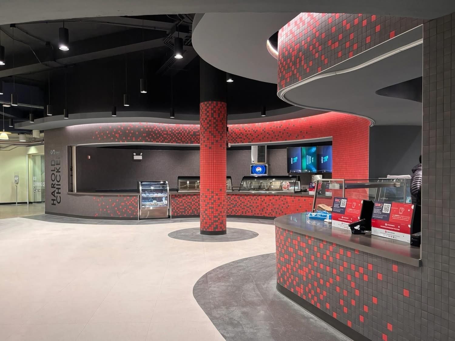 Interior of a food service area with red tiled counters, black ceiling, and display shelves.