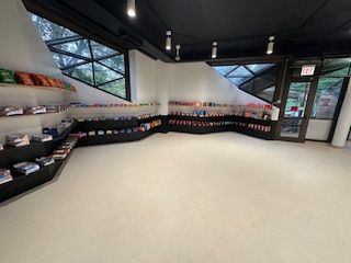 Interior shop with merchandise on shelves, white floor, black walls, triangular windows, and an exit door . UIC