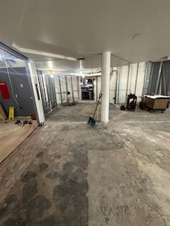 Construction site, interior view; exposed walls and concrete floor. A worker stands amidst the unfinished space with tools.UIC