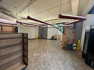 Empty store interior with dark red angular overhead lights, brown floors, and empty shelves.UIC