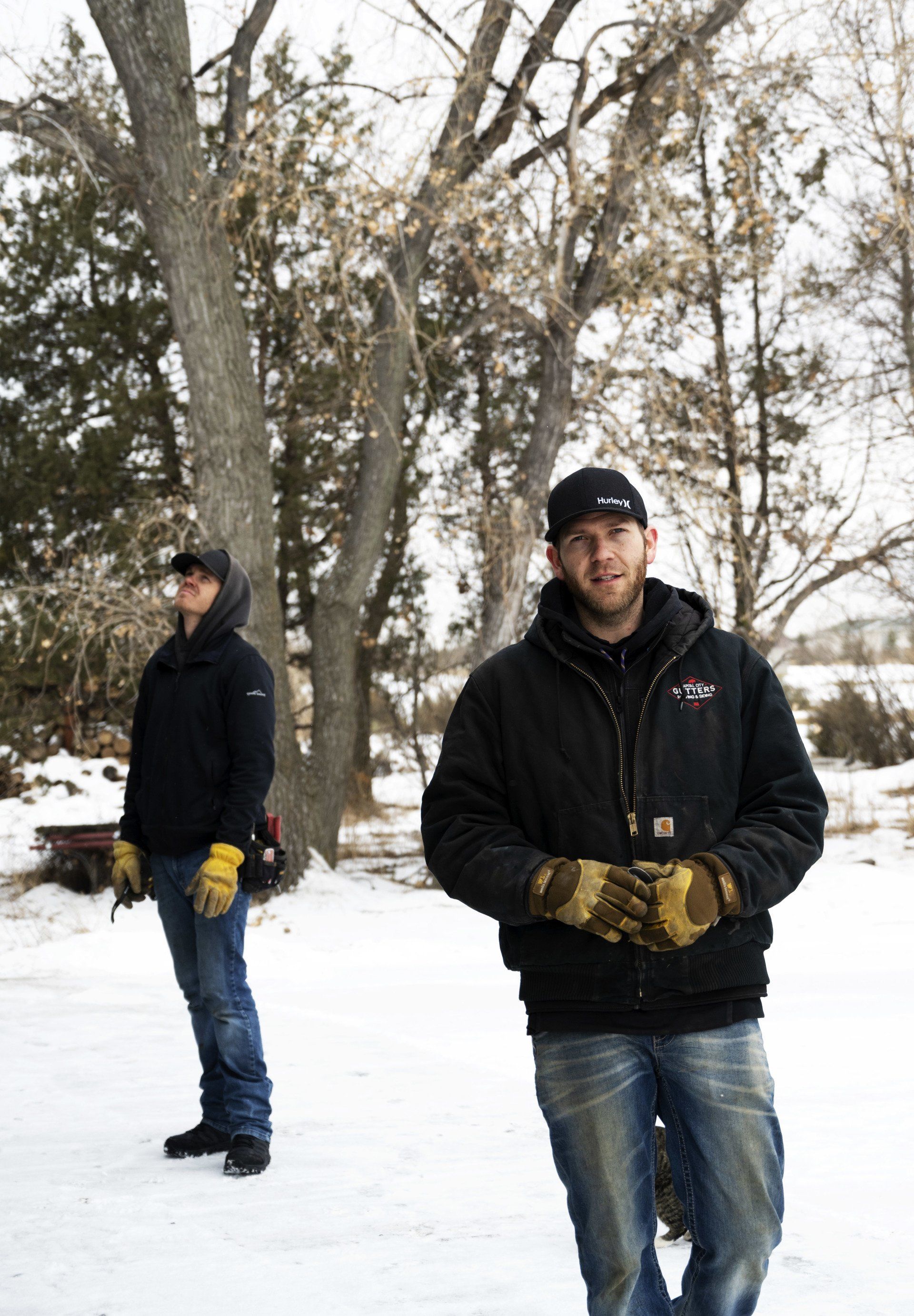 two men are standing in the snow wearing gloves