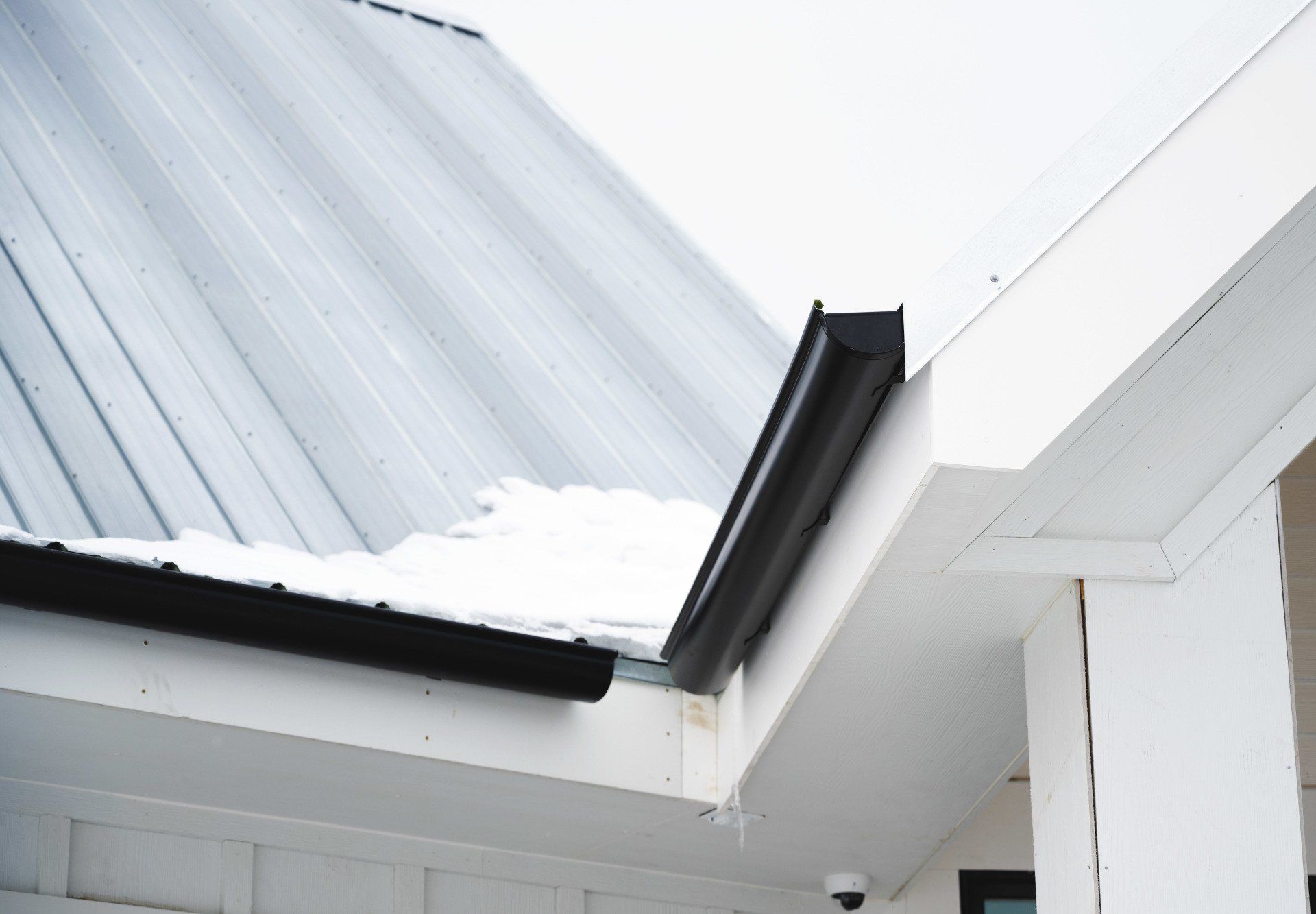 a white house with a metal roof and a black gutter
