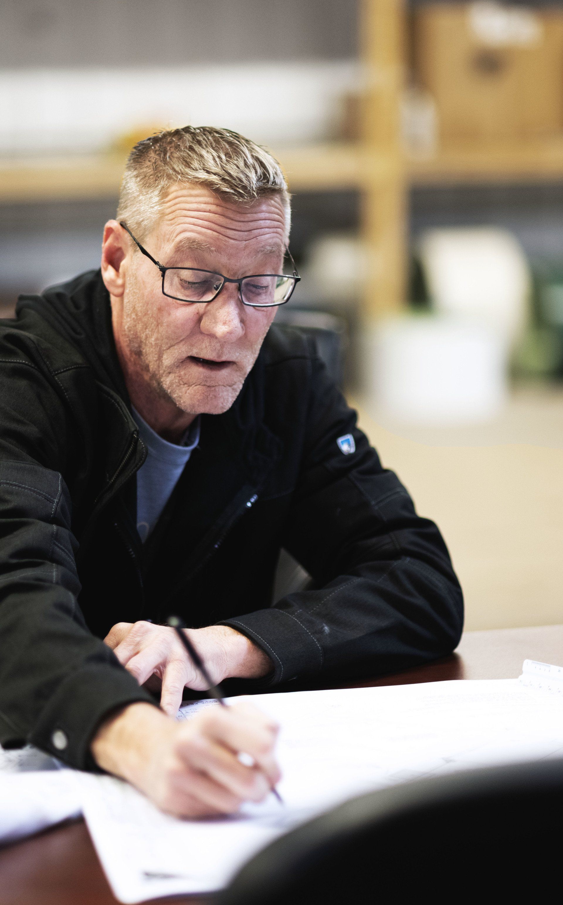 a man is sitting at a table writing on a piece of paper .