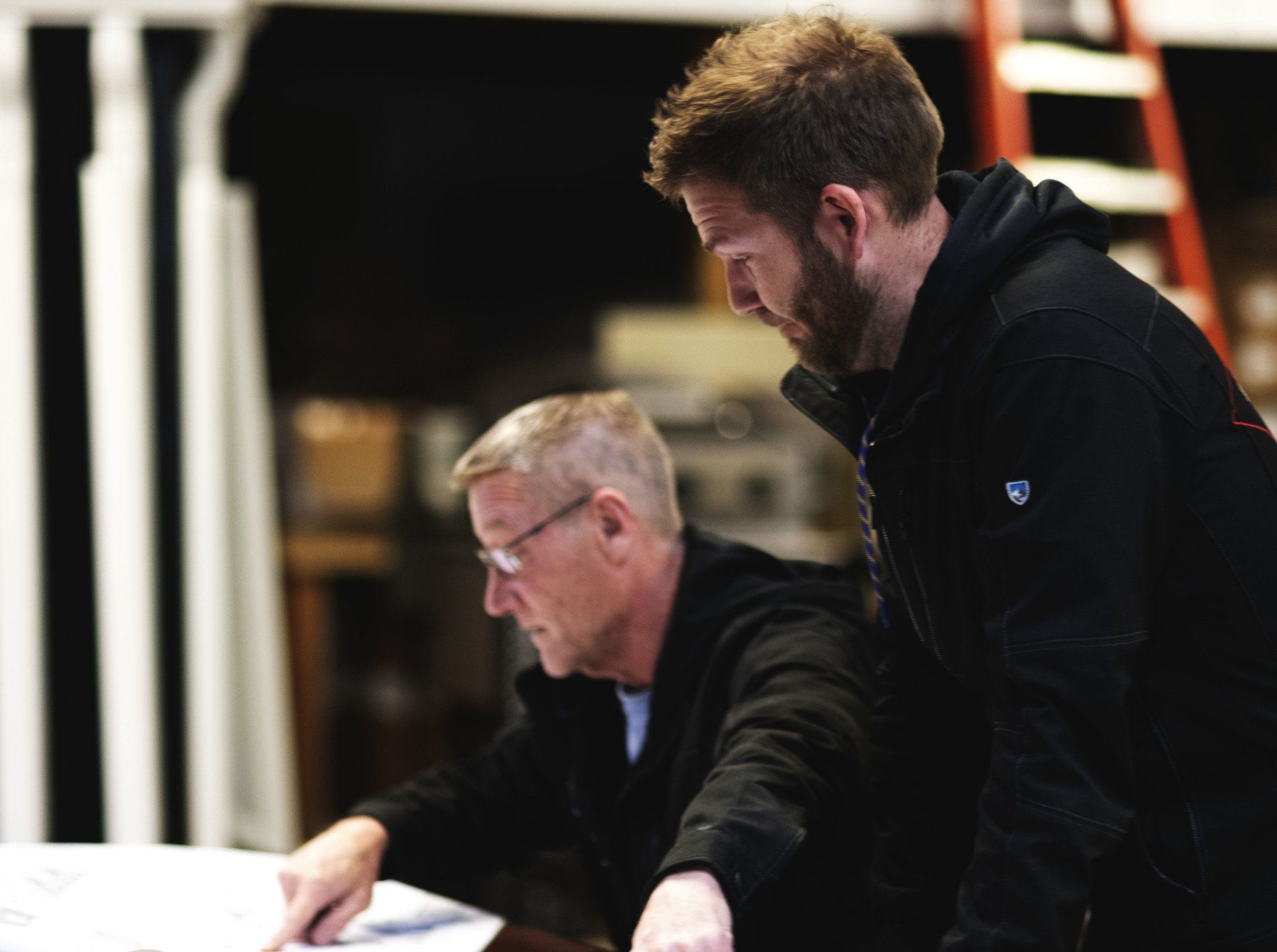 two men are looking at a blueprint on a table .
