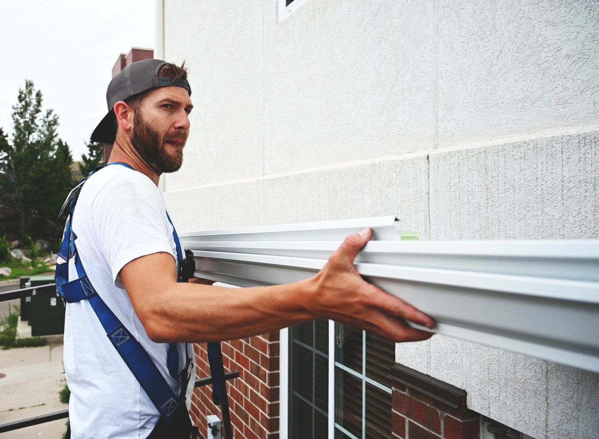 a man is installing a gutter on the side of a building .