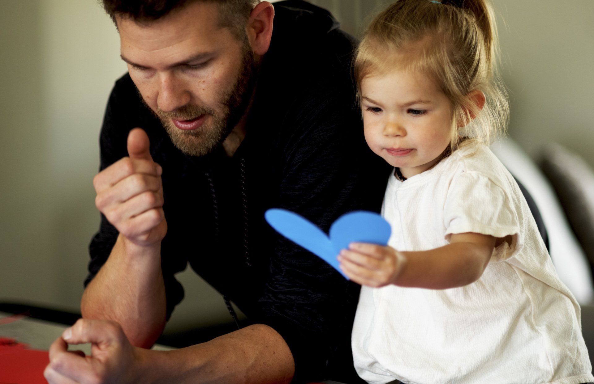 a man and a little girl are playing with a blue heart .