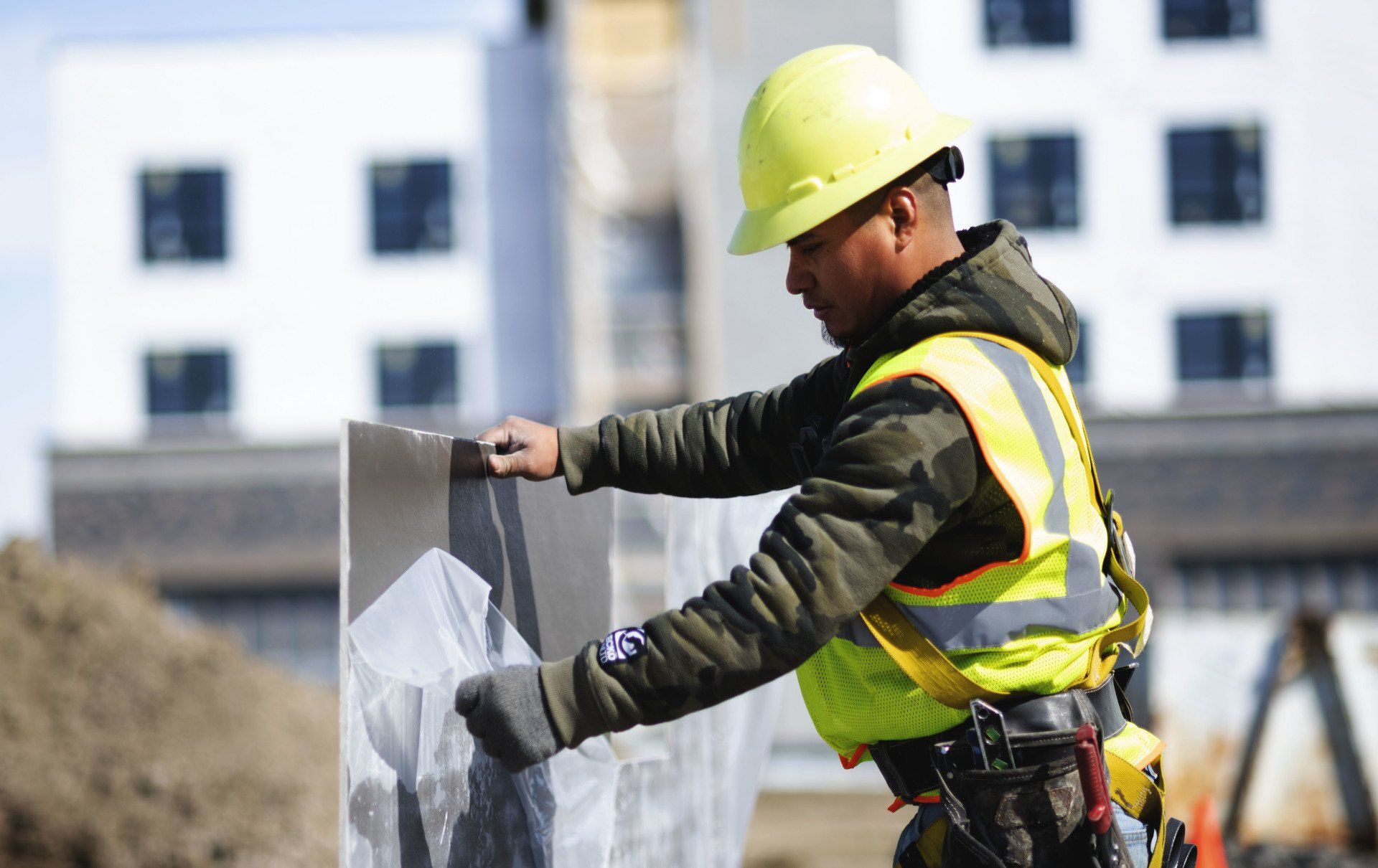 a construction worker wearing a hard hat and safety vest is working on a wall .