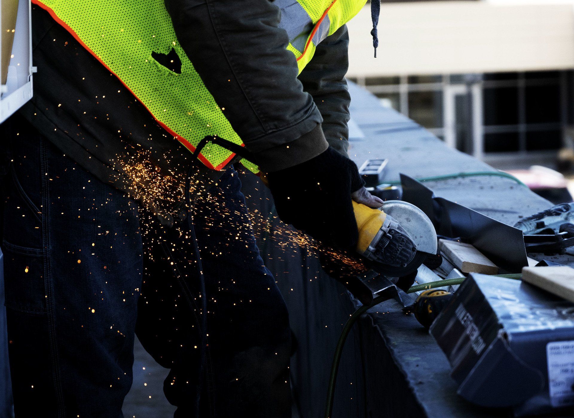 a man wearing a safety vest is using a grinder