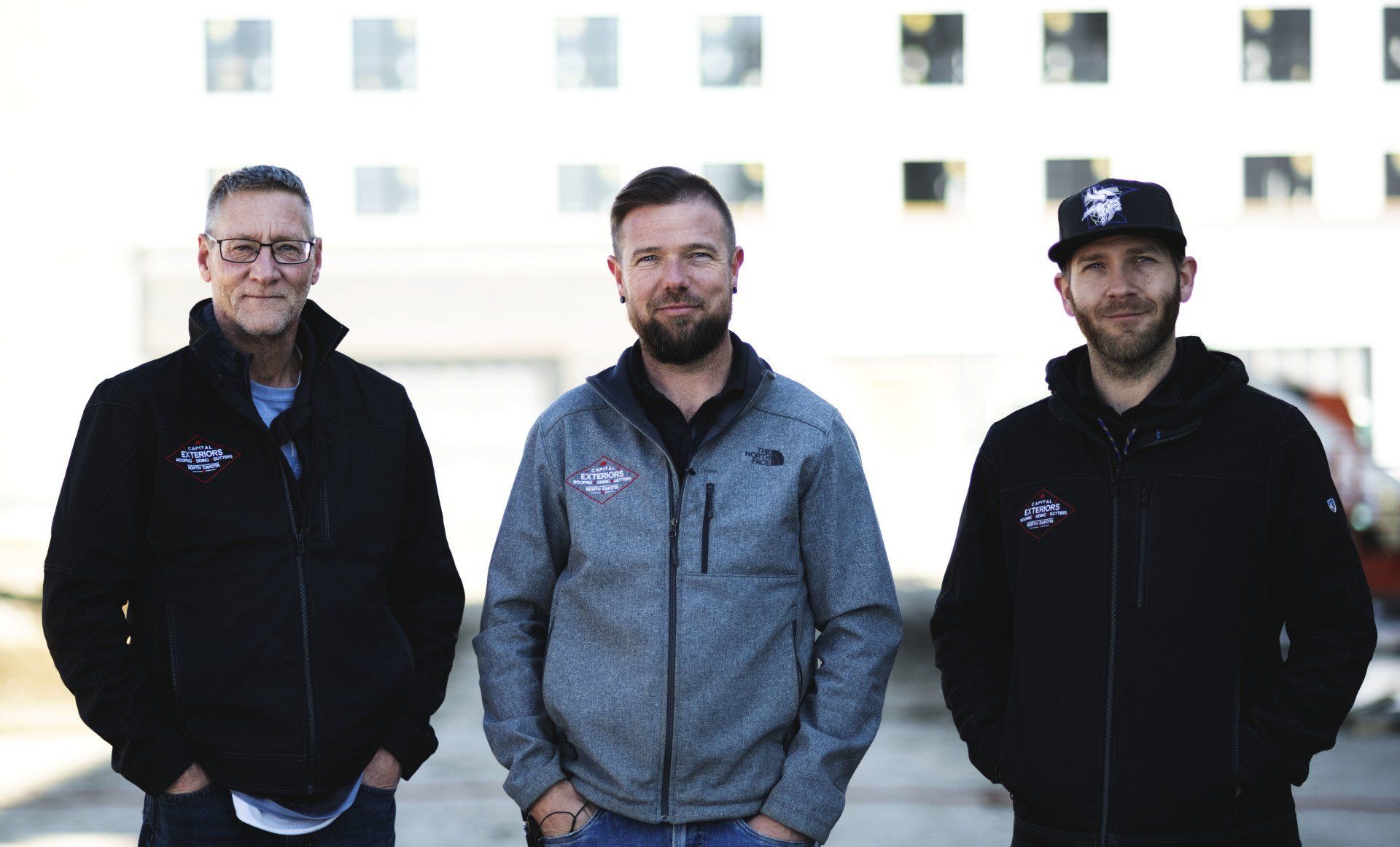 three men are standing next to each other in front of a building .