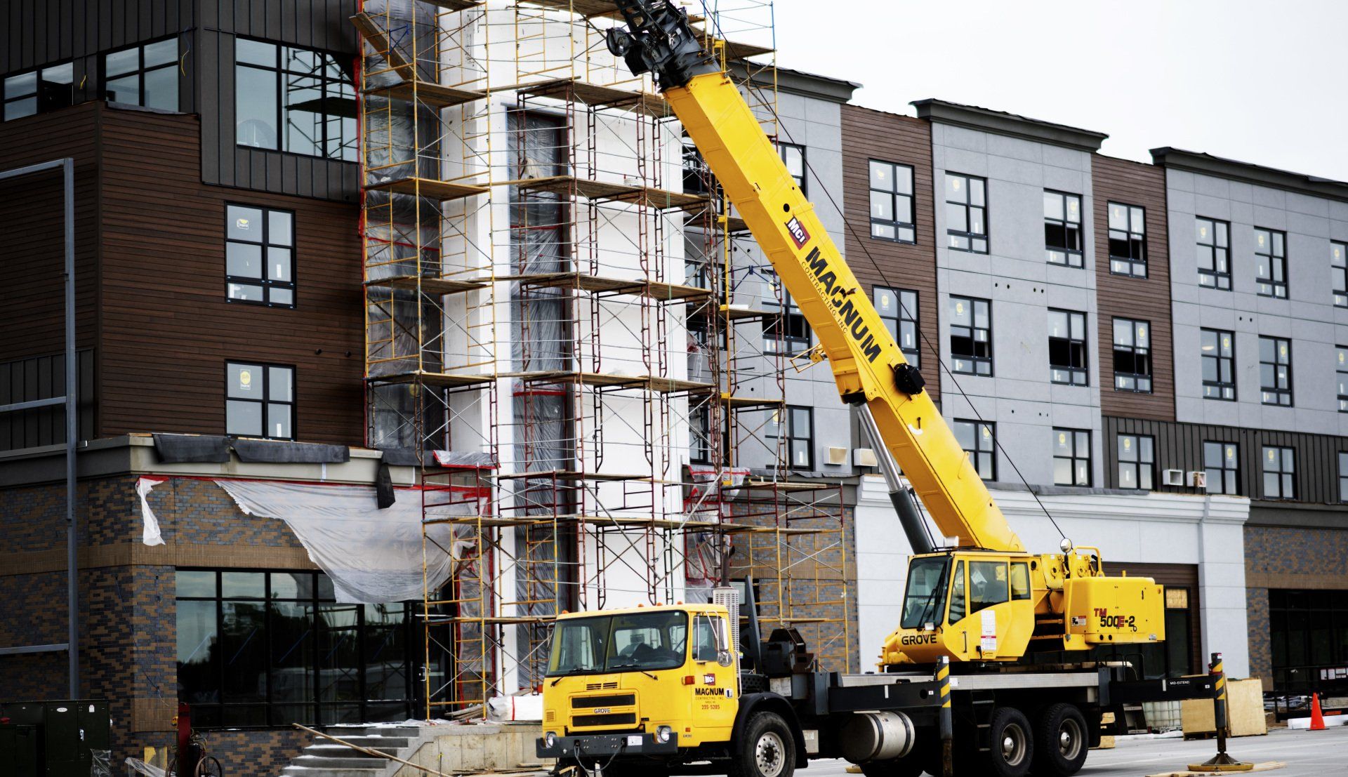 a yellow crane is parked in front of a building under construction