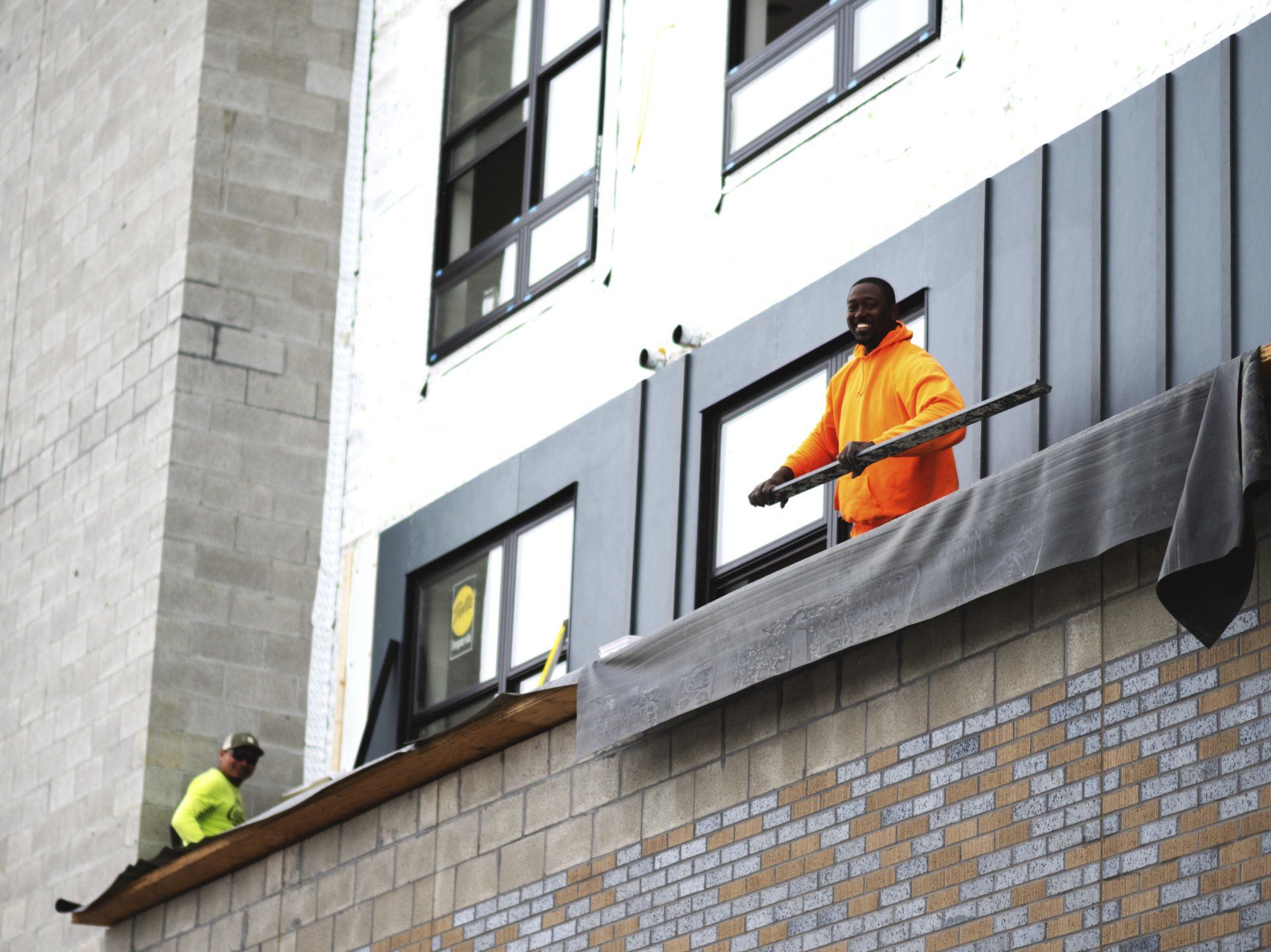 two construction workers are working on the side of a building