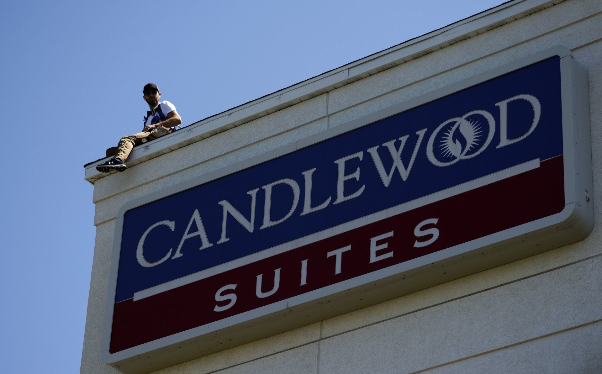 a man sits on the roof of a candlewood suites hotel
