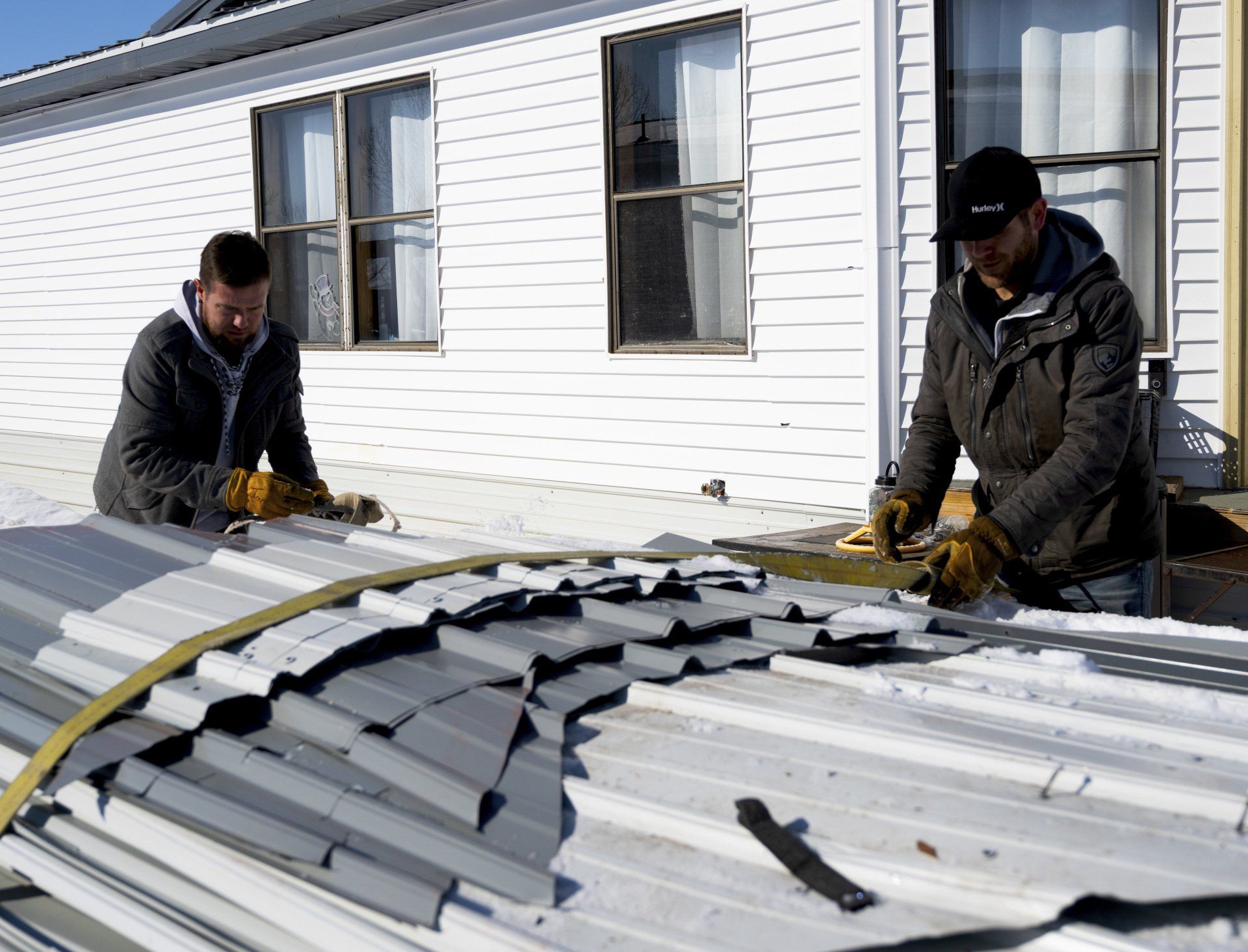 two men are working on the roof of a house .