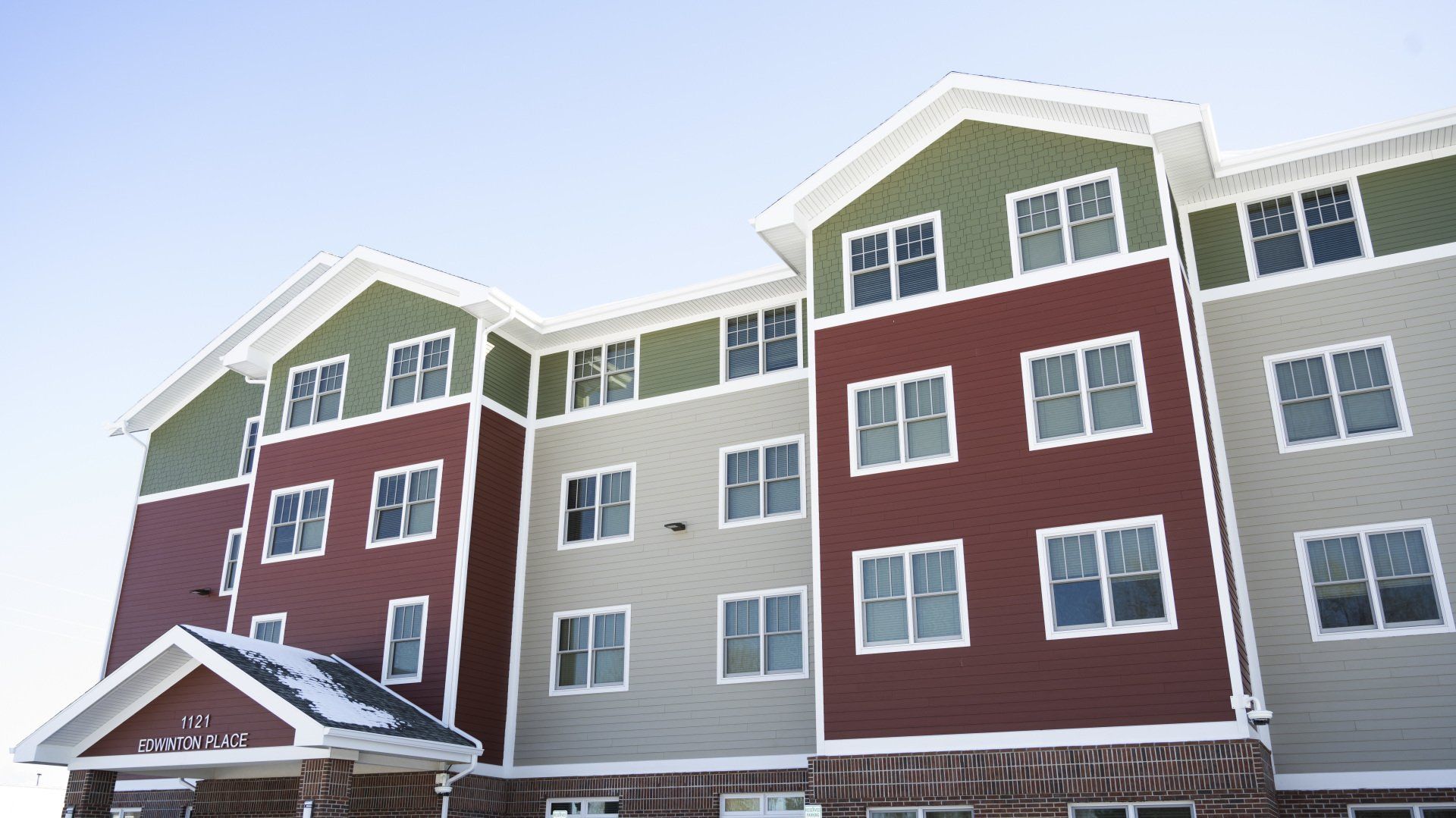 a red and green apartment building with a blue sky in the background