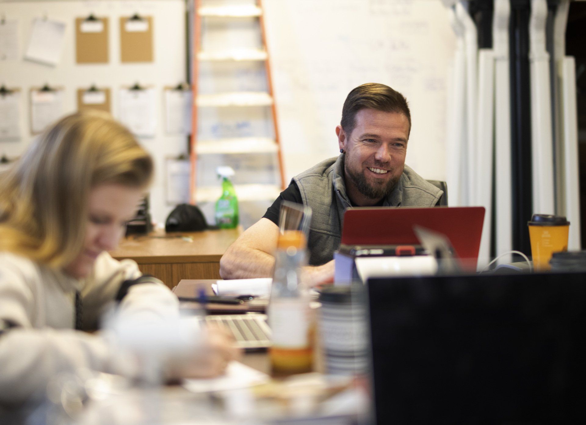 a man and a woman are sitting at a table using laptops .