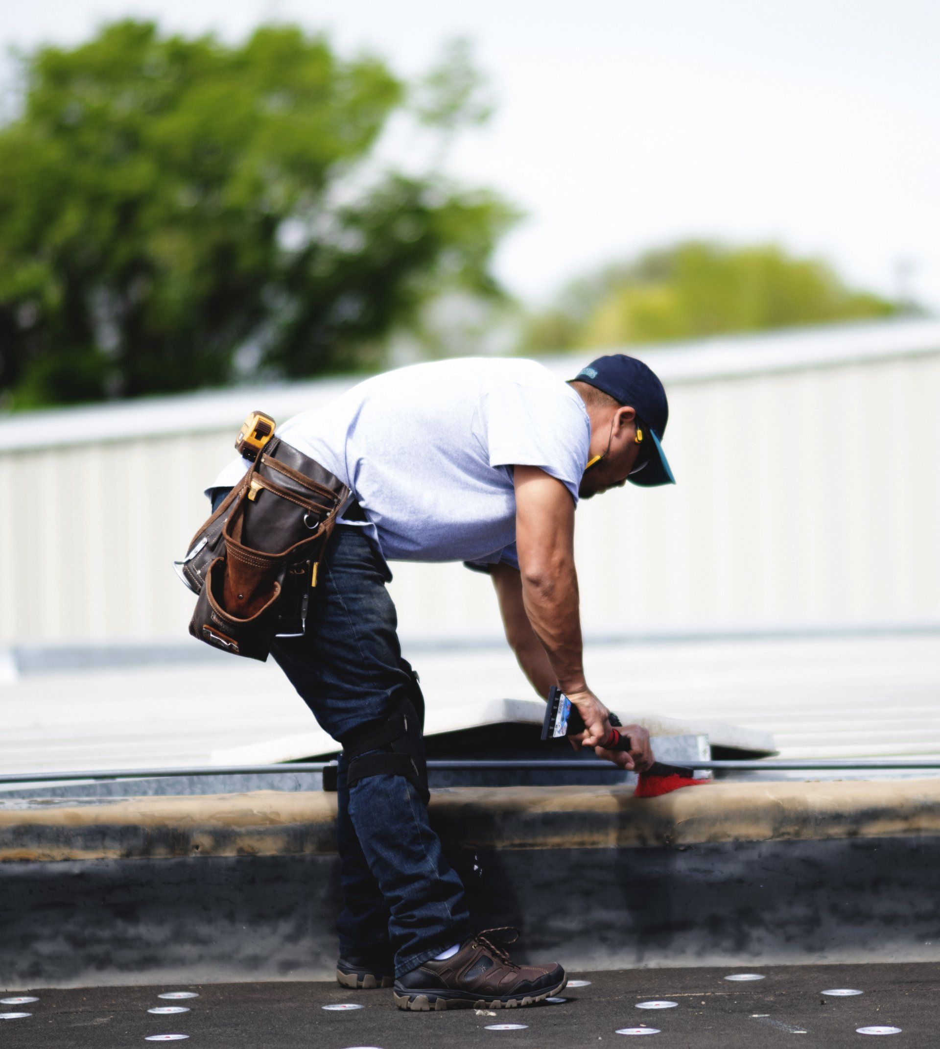 a man is working on a roof with a tool belt around his waist .