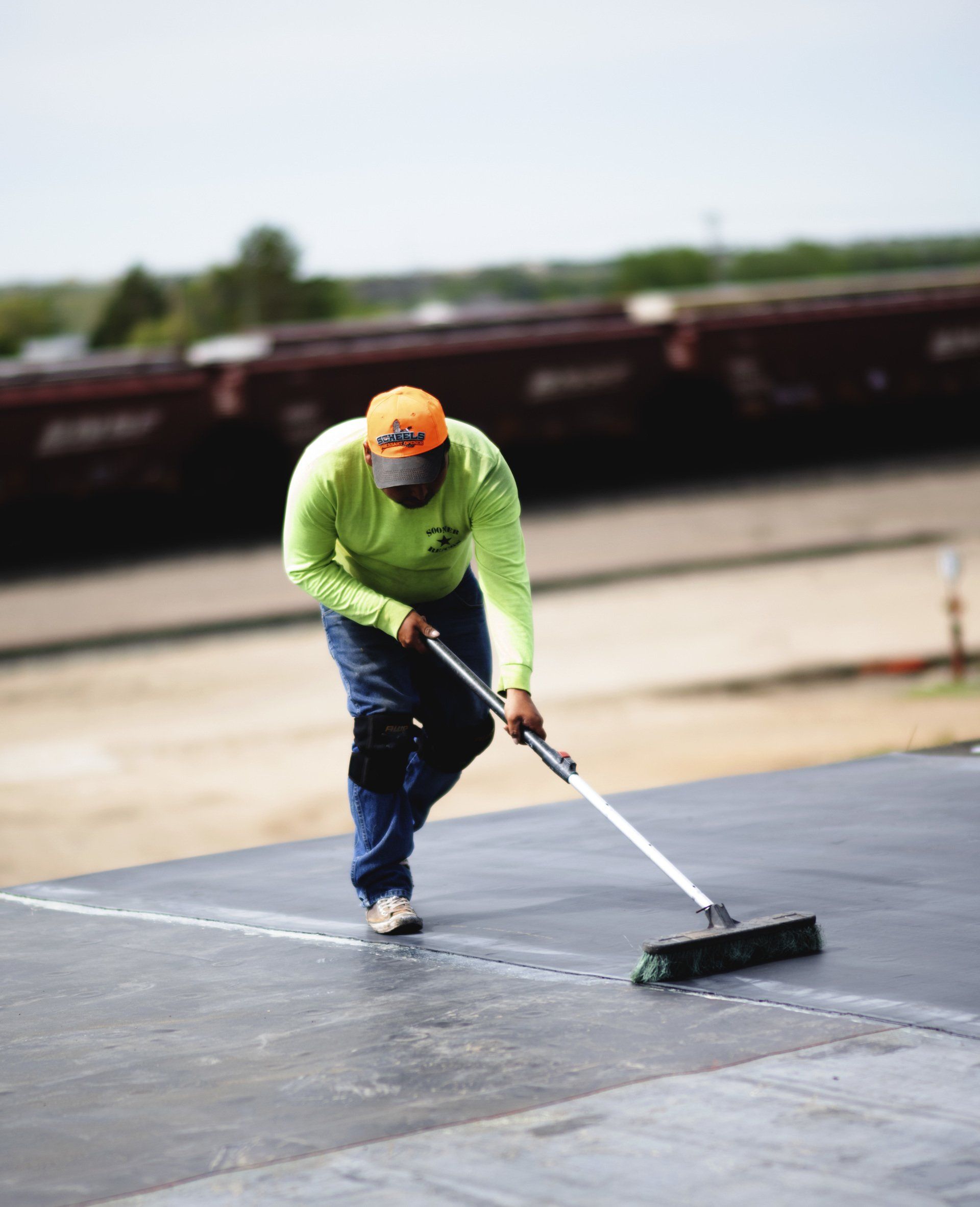 a man wearing an orange hat is sweeping the ground with a broom