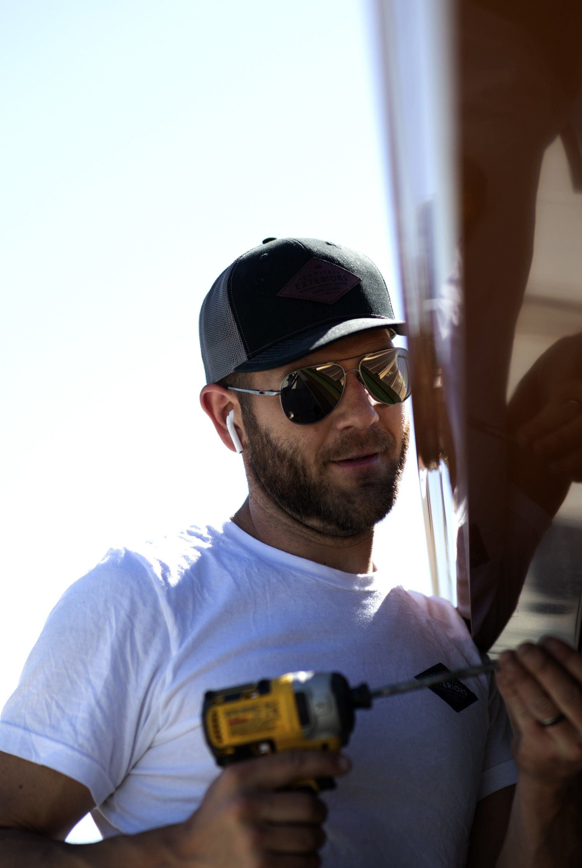 a man wearing sunglasses and a hat is using a drill