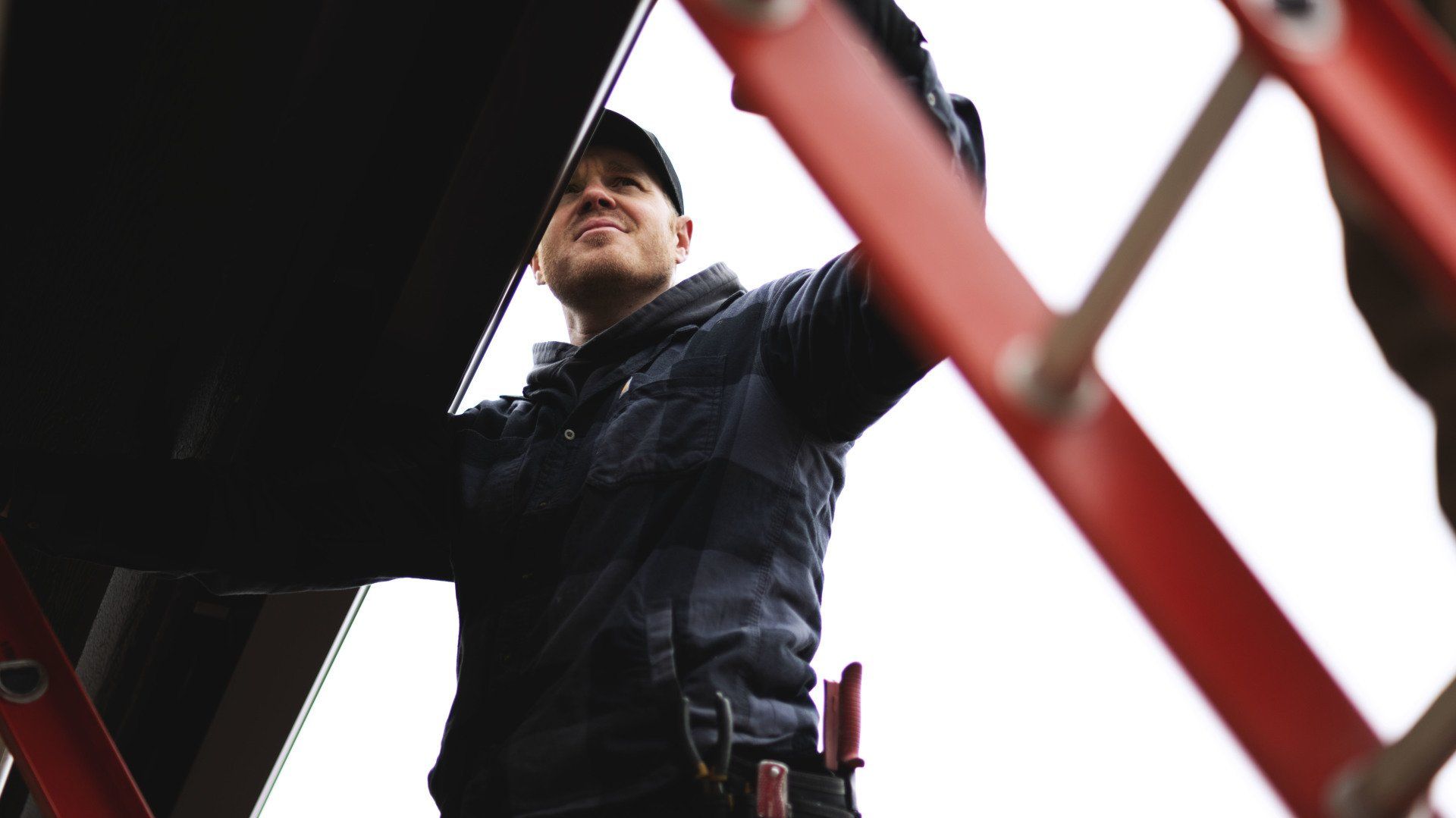 a man is standing on a ladder looking up at something