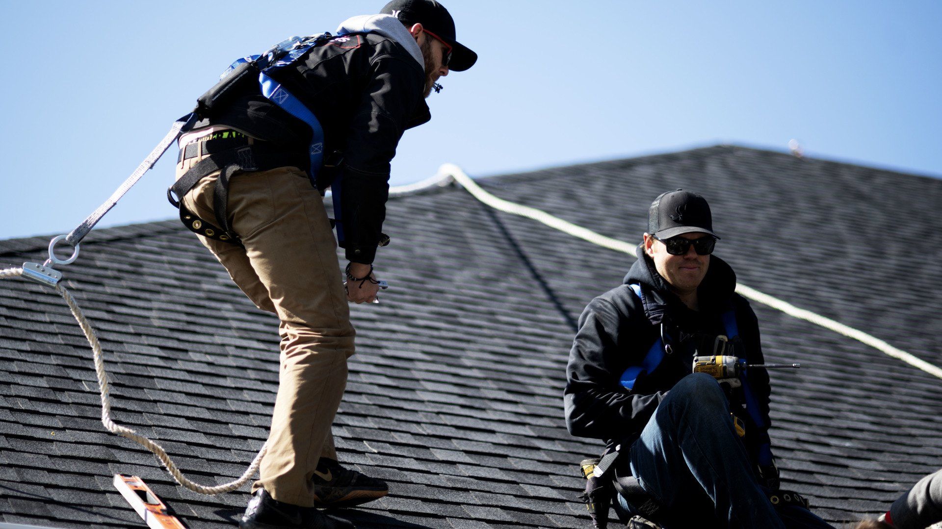 a man is standing on top of a roof while another man sits on the ground .