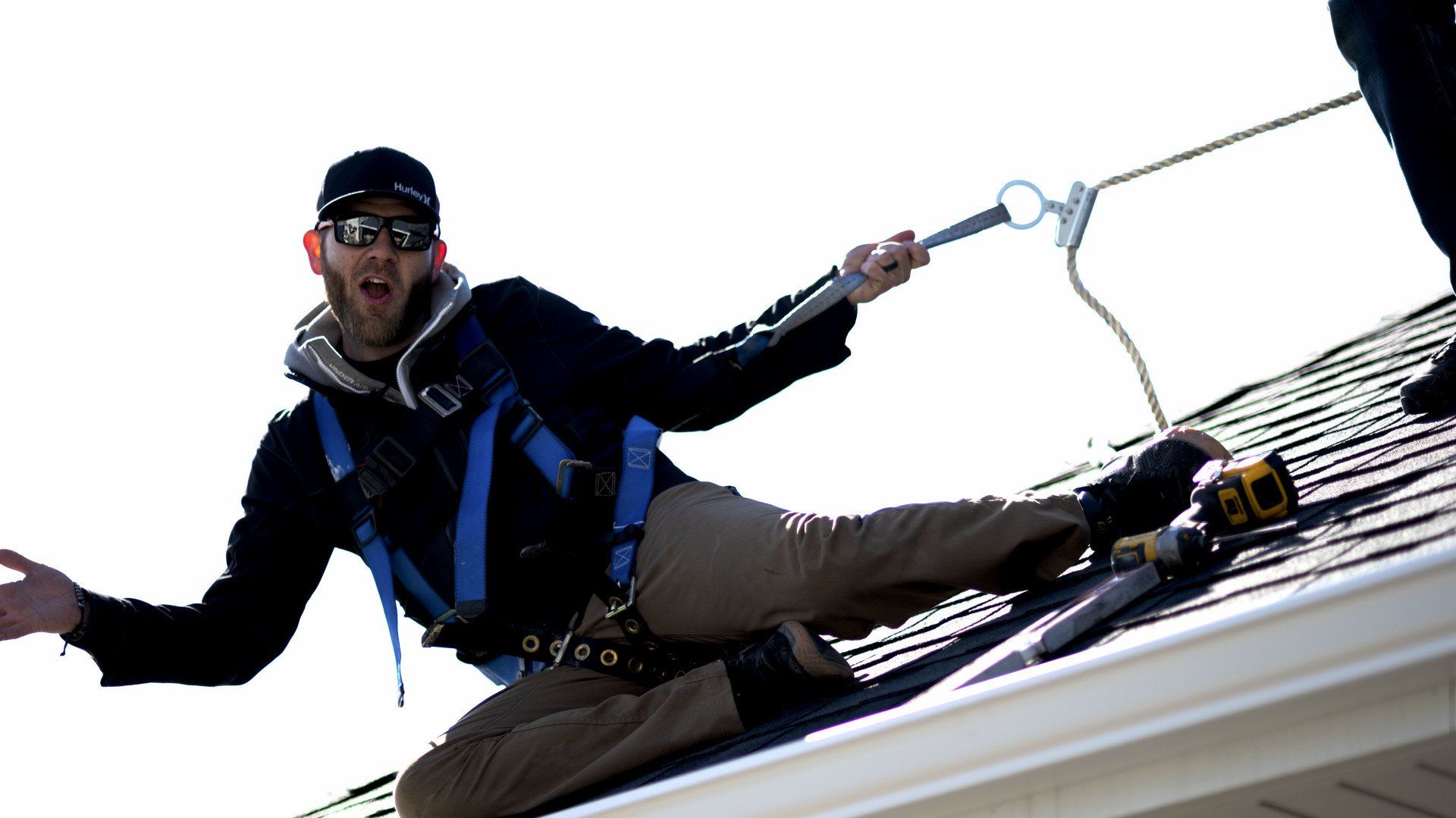 a man is sitting on a roof holding a rope