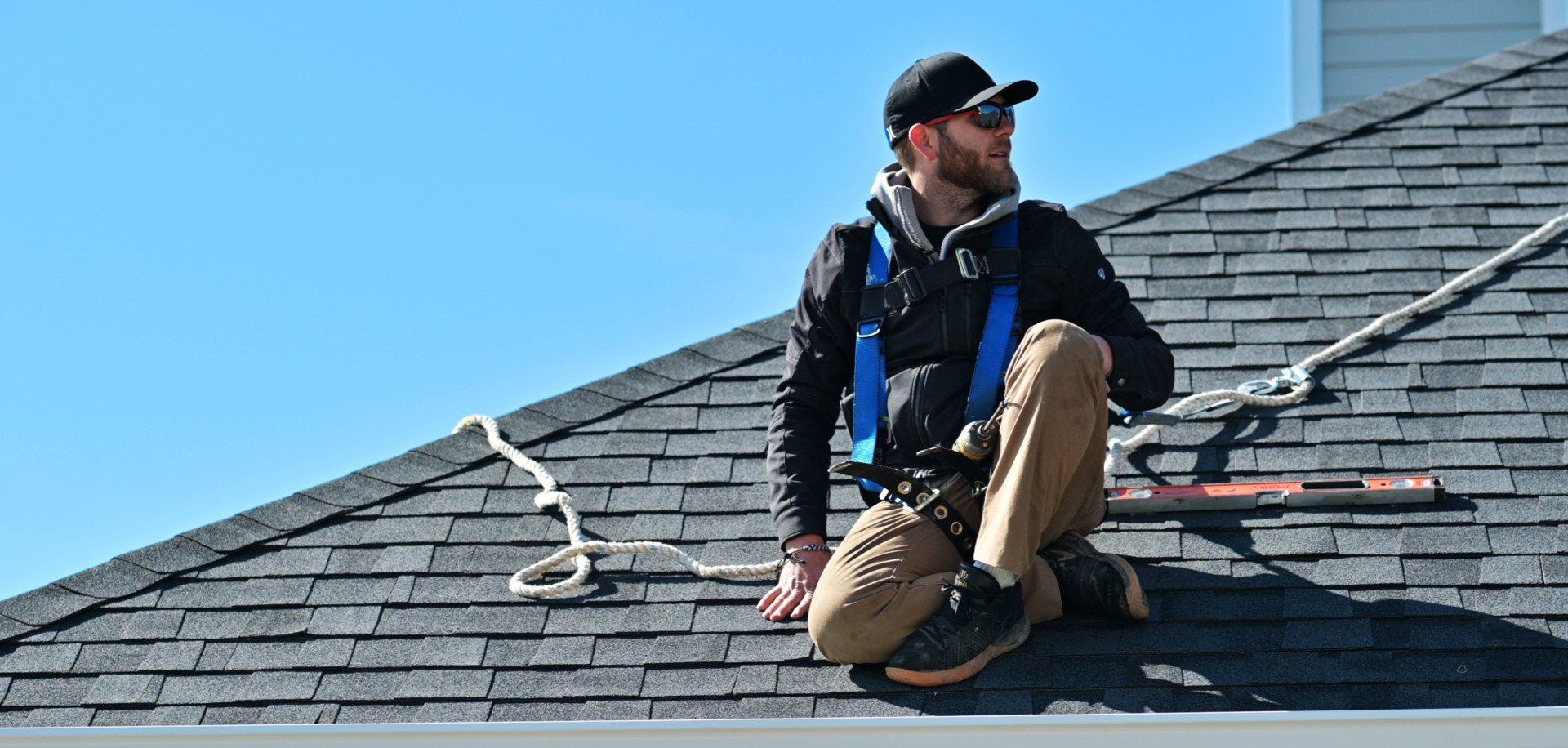 a man is sitting on top of a roof wearing a harness .
