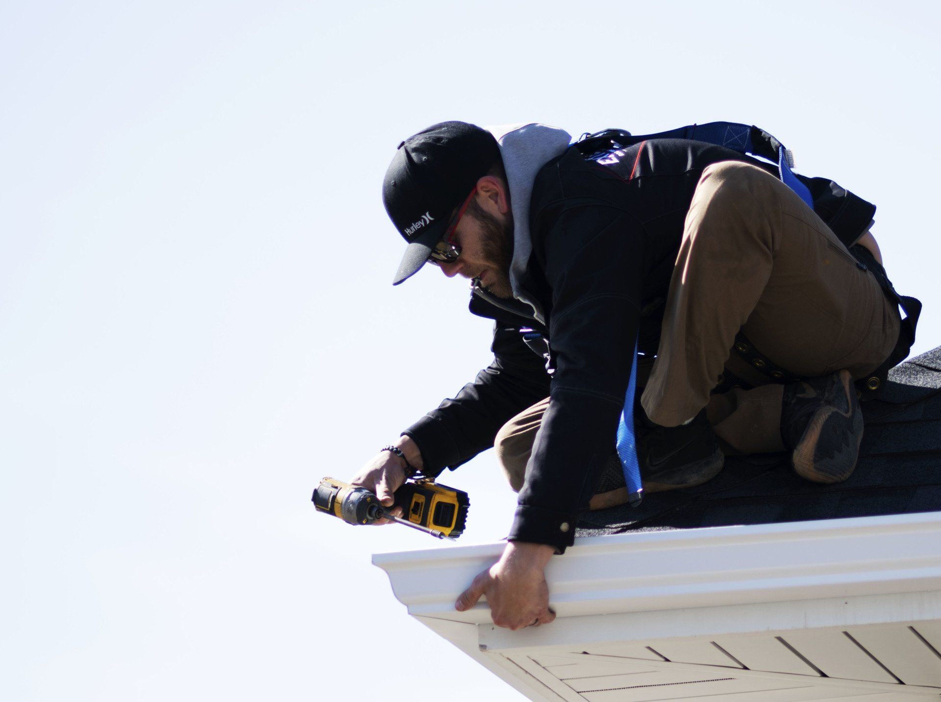 a man is working on a roof with a drill .