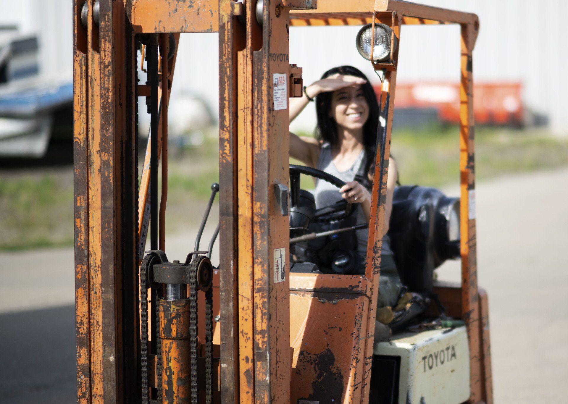 a woman is driving a forklift in a parking lot .